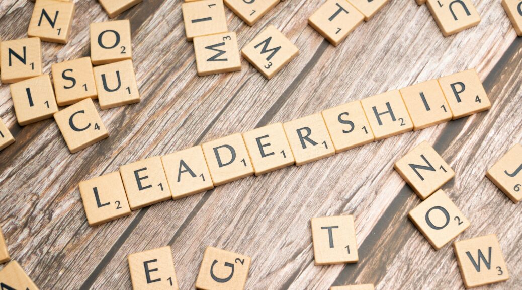 Scrabble tiles spelling out the word "Leadership" on a wooden surface