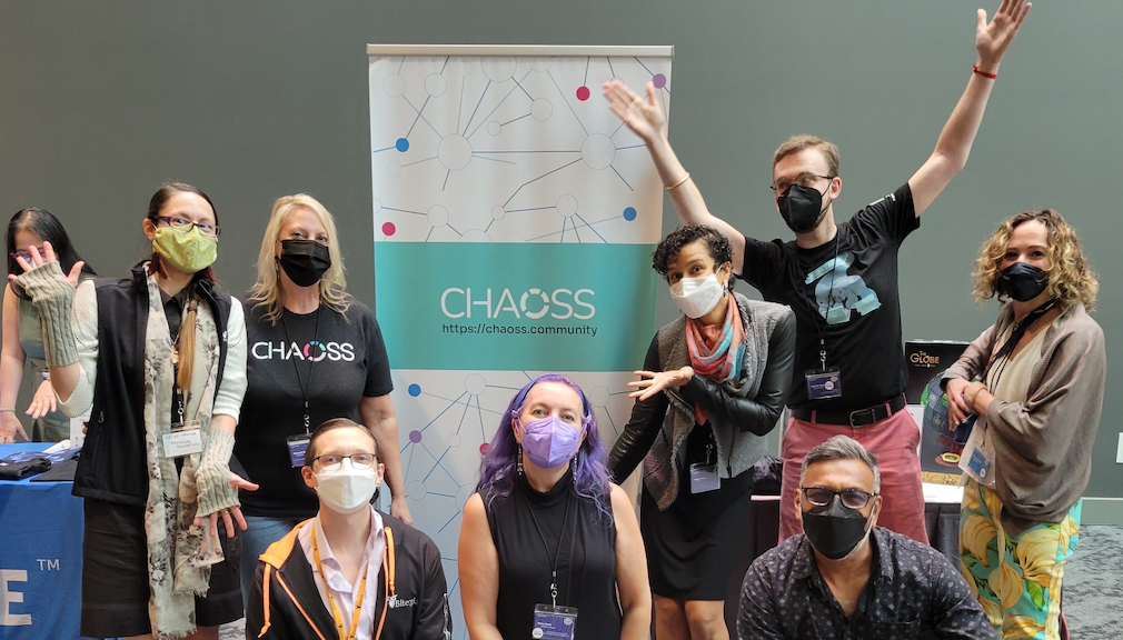 CHAOTICs wearing masks and having fun in from the the CHAOSS popup sign at the FOSSY event in Portland